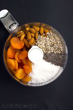 an overhead view of nuts, rice and other ingredients in a food processor bowl on a black background