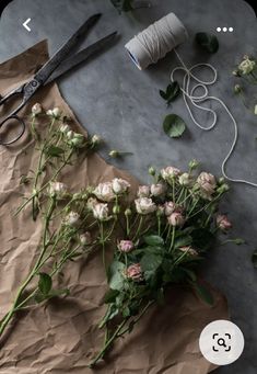 some flowers are laying on a piece of brown paper next to a pair of scissors