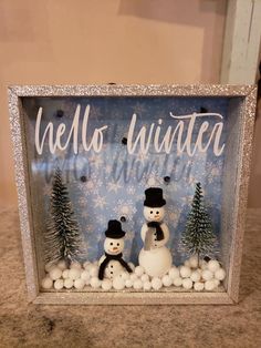 a snowman and two snowmen in front of a sign that says hello winter