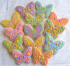 decorated cookies are arranged in the shape of butterfly's on a white tablecloth