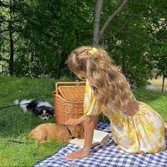 a woman sitting on top of a blue and white checkered blanket next to two dogs