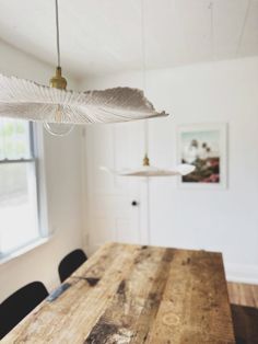 a wooden table with black chairs and a white feather hanging from it's center