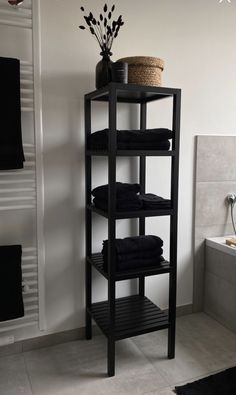 a black shelf with towels and a basket on top