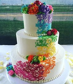 a multi - tiered wedding cake decorated with colorful flowers and pearls on a table