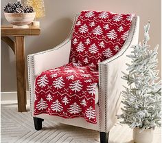 a red and white chair sitting next to a christmas tree on top of a rug