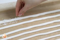 a person is placing white piping on top of the dough sheet with their hand