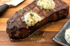 a piece of steak on a plate with mashed potatoes and a knife next to it