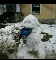 a child is sitting on top of a snowman