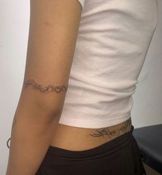 a woman with a tattoo on her left arm and the other arm behind her back