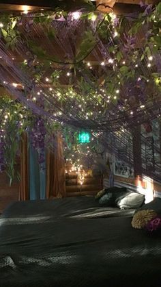 there is a bed with purple flowers on the headboard and lights hanging from the ceiling