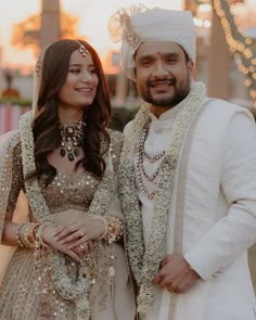 a man and woman standing next to each other in formal wear, smiling at the camera