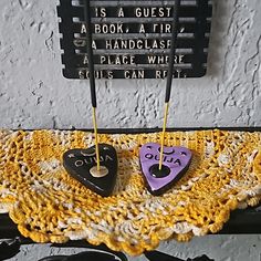 two small black and purple hearts are on a doily next to a sign that says it is a guest