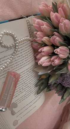 a bouquet of tulips next to an open book with pearls on the cover