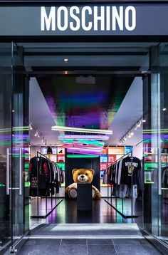 a teddy bear sitting in front of a moschino store