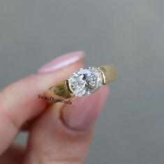 a person holding a ring with a diamond in it's middle and gold band