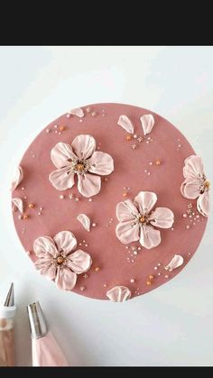 a cake with pink icing and flowers on it next to a pair of scissors