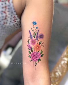 a woman's arm with flowers and leaves tattooed on the left side of her arm