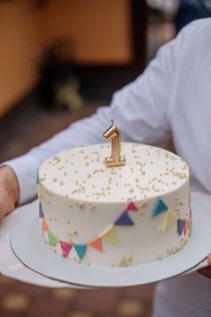 a person holding a cake with a number one on it