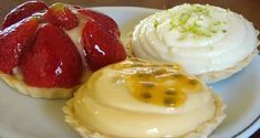 three pastries on a white plate with strawberries and whipped cream in the middle