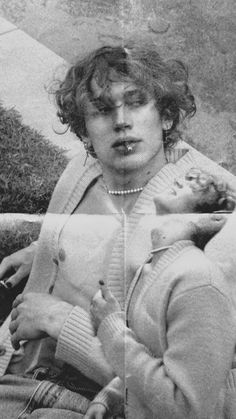 an old black and white photo of a woman holding a baby in her arms while sitting on the ground