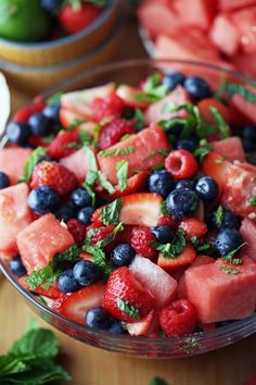 watermelon, blueberries and raspberry salad in a glass bowl on a wooden table