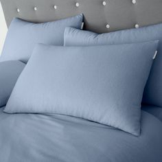 blue sheets and pillows on a bed with polka dot headboard in the backround