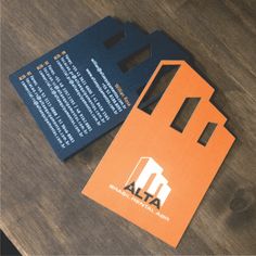 an orange and black business card on top of a wooden table