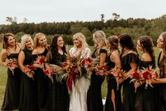 a group of women standing next to each other in front of a lush green field