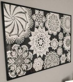 a black and white wall hanging with crocheted doily on it's side