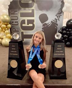 a woman sitting on the floor with two trophies