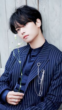 a young man wearing a suit and holding a flower