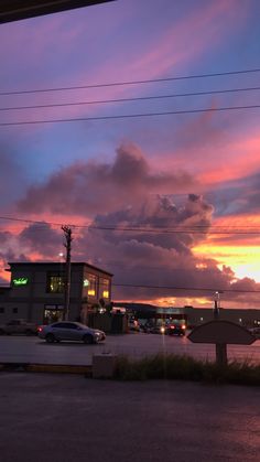 the sun is setting over some buildings and cars