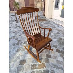 a wooden rocking chair sitting on top of a cobblestone street