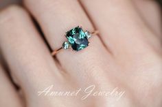 a woman's hand holding a ring with an oval shaped green stone on it