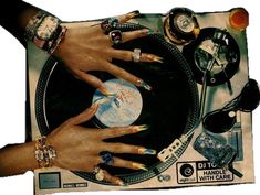 several hands on top of a record player surrounded by jewelry and other items that include rings