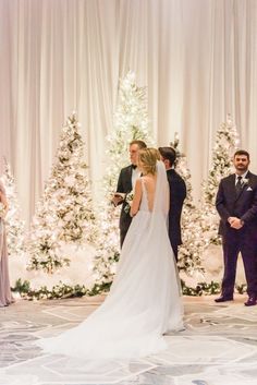 a bride and groom standing in front of a decorated christmas tree at their wedding ceremony