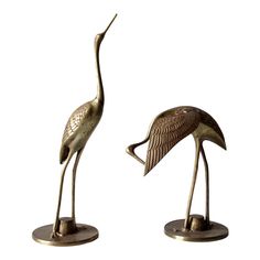 two bronze statues of birds standing next to each other on metal bases with white background