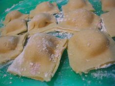 several uncooked ravioli on a green plate with powdered sugar sprinkles