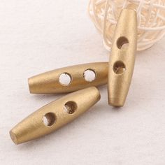 three gold colored metal beads with holes in them