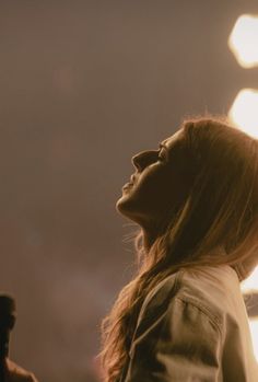 a woman standing in front of a street light with her head tilted to the side