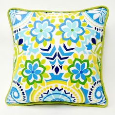 a blue and yellow pillow with green trim on the bottom is sitting on a white surface