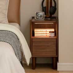 a nightstand with headphones on it next to a bed