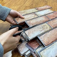 a person using scissors to cut brick tiles