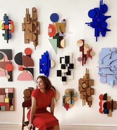 a woman in a red dress is sitting on a chair next to an art work