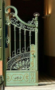 an ornate iron gate in front of a building with light colored walls and flooring