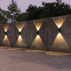 a wall with several lights on it and some trees in the background