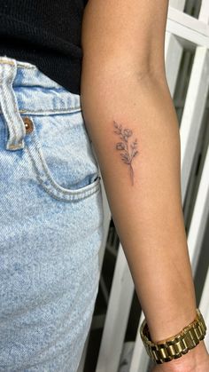 a woman's arm with a small flower tattoo on the left side of her arm