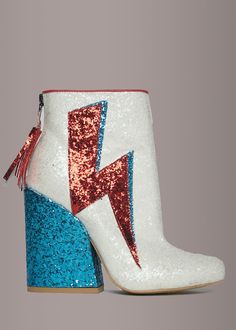 These super-rad David Bowie boots by Y.R.U are dedicated to a starman who sprinkled stardust through our universe. These insanely sparkly ankle boots feature a white glitter-covered construction, pointed toe, thick 4 1/2 inch blue glitter block heel, red and blue sparkle lightning applique on the outer, elasticized side detail and zip back closure with glittery tassel pull tab. Available in sizes 6, 7, 8, 9 and 10. Made out of man made materials. Blue Glitter Heels, Glitter Wallpaper Iphone, Glitter Ankle Boots, Daily Shoes, Glitter Fashion, Ziggy Stardust, Glitter Heels, New Rock, Glitter Shoes