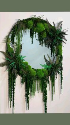 a circular mirror with green plants hanging from it