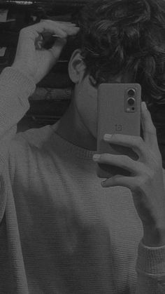 black and white photograph of a person holding a cell phone up to their face while taking a selfie